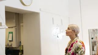 Henkilö katsoo seinäkelloa sisätilassa.