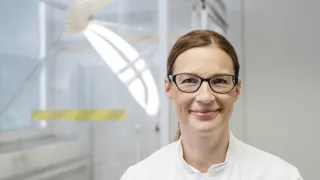 Hymyilevä sairaanhoitaja laboratorion edessä