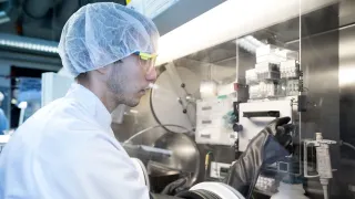 A scientist adjusting switch in fume hood in lab cleanroom.