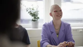 Hipsterinainen hymyilee toimistohuoneessa