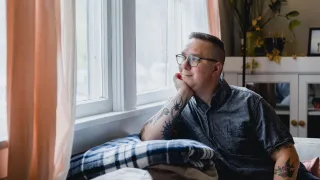 Mies katselee ulos ikkunasta kotona